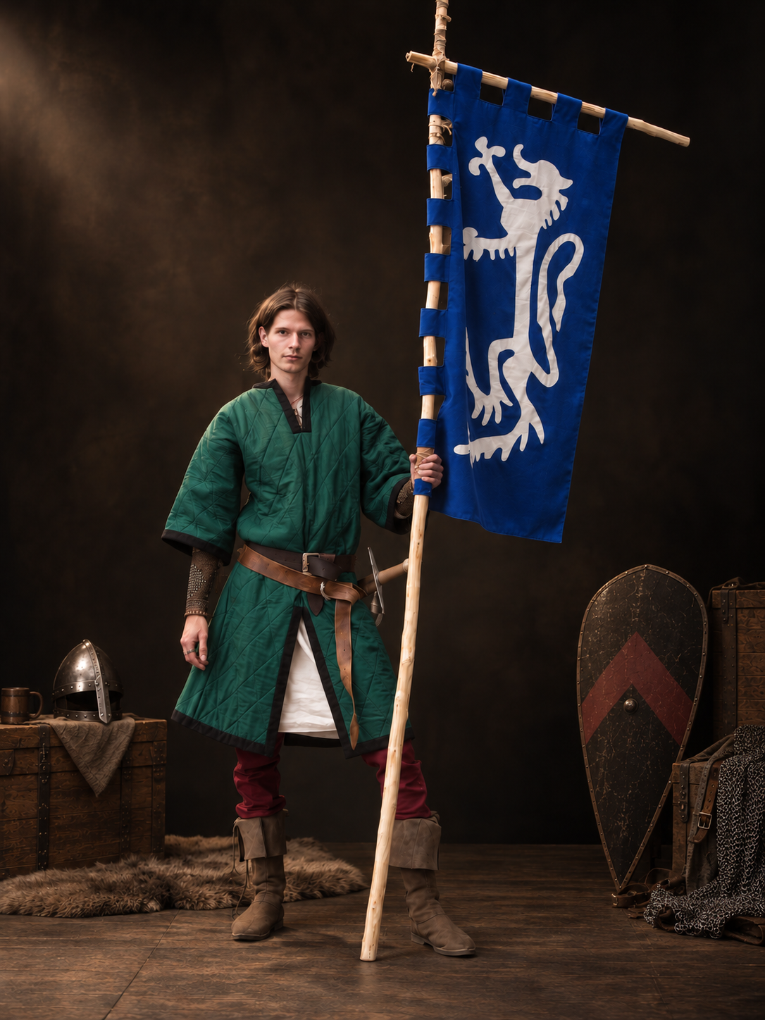 Standing in reenactment garb holding a banner, a hand-painted shield resting nearby